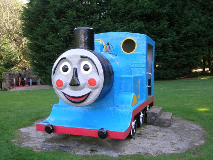 A photo of Thomas the Tank Engine in a playground with a terrifying face.