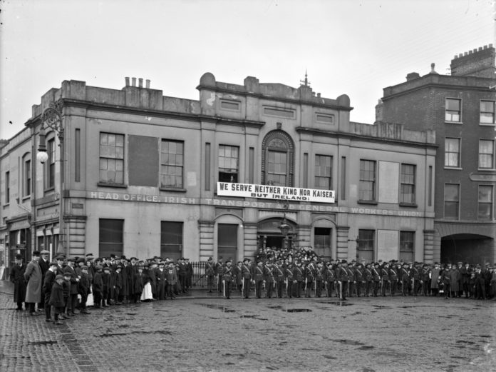 Irish Citizen Army group outside Liberty Hall. Group are lined up outside ITGWU HQ under a banner proclaiming 