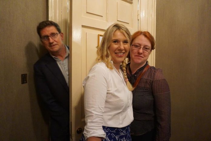 Eamon Ryan pops his head behind a door as Senator Alice Mary Higgins and another activist take a photo.