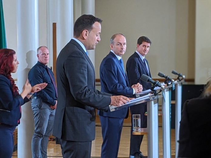 Leo Varadkar, Michael Martin and Eamon Ryan stand at lecterns while ISL translates stand behind.