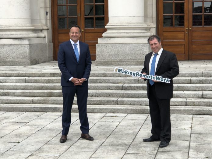 Leo Varadkar stands in front of Government Buildings while another man holds a sign saying #MakingRemoteWork