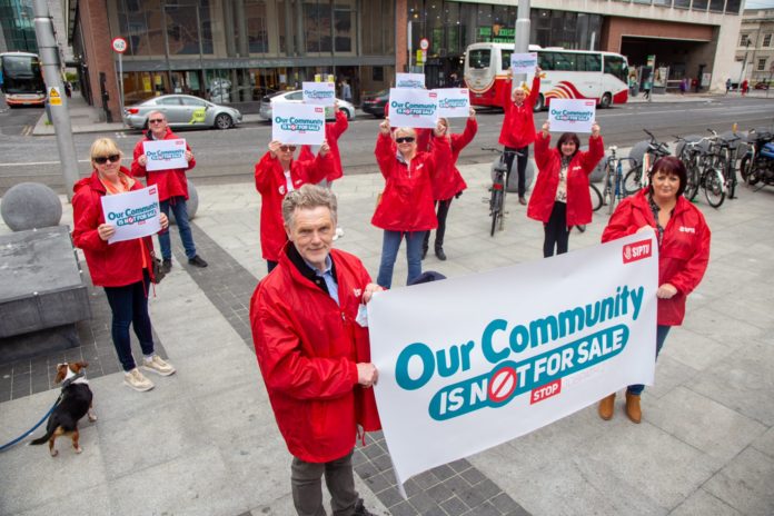 Several SIPTU members in red coats hold up banners and placards reading 