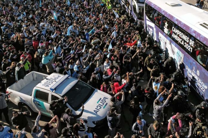 An image of a huge crowd gathering around the Argentinian football team's bus