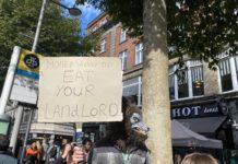 Why no one liked the housing announcements in Budget 2023 At a cost of living demonstration a demonstrator in a wolf mask holds a sign that says "money saving tip: eat your landlord".